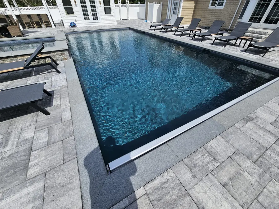 Pool with a dark liner and grey paver deck