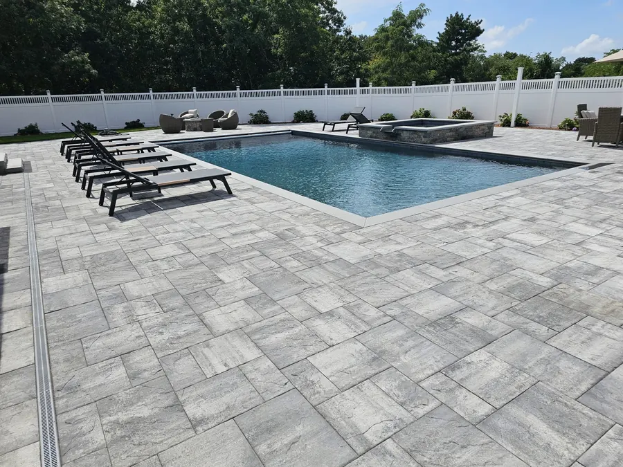 Pool with lounge chairs on a paver deck