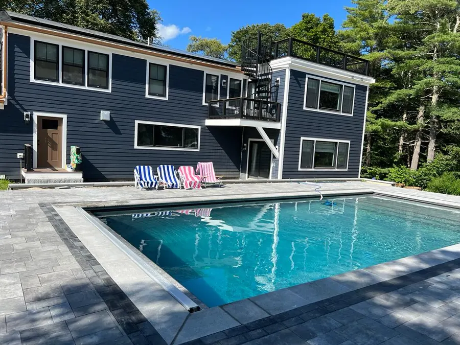 Finished pool in front of a navy blue house