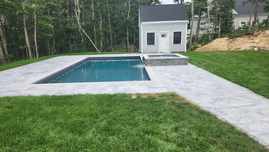 Pool beside a white pool house and lawn